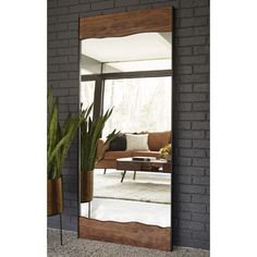 a large mirror sitting on top of a brick wall next to a potted plant