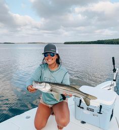 a woman holding a fish while sitting on a boat