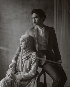 an old black and white photo of a man and woman sitting next to each other