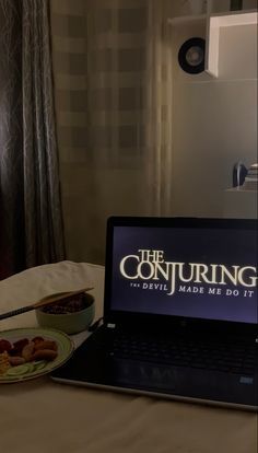 an open laptop computer sitting on top of a bed next to a plate of food