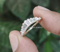 a close up of a person's hand holding a ring with three stones on it