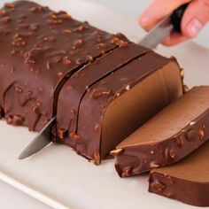 someone cutting into a chocolate cake with a knife