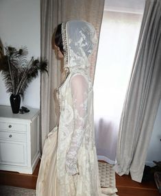 a woman in a wedding dress looking out the window