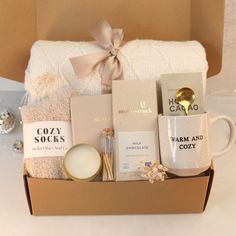 the gift box contains two mugs, candles, and other personal care items in it