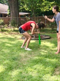 two women are playing frisbee golf in the yard while another woman looks on