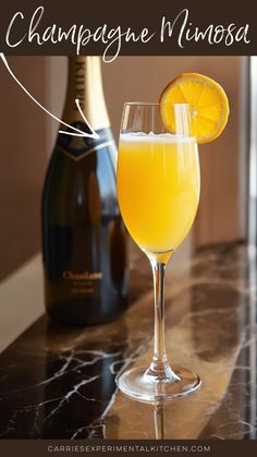 a glass filled with orange juice next to a bottle