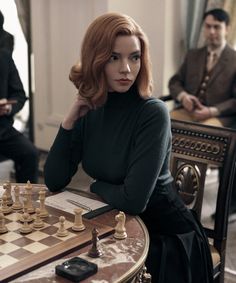 a woman sitting at a table with chess pieces