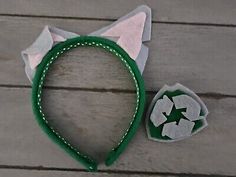 a green and white cat headband next to a small patch on a wooden surface