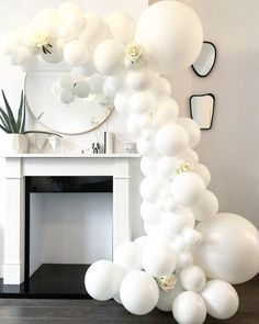 a bunch of balloons that are in front of a fireplace with a mirror on the wall