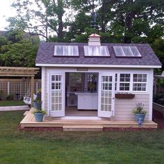 a small white shed sitting on top of a lush green field