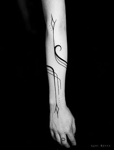 a black and white photo of a person's arm with an arrow tattoo on it