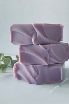 three bars of soap sitting on top of each other next to some green leafy plants