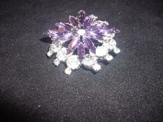 "This stunning two level brooch is in the form of a blazing star and uses round stones on the base level and amethyst marquise stones for the top level. The center has a round crystal stone. It measures 2\" wide by 3/4\" high and is in excellent undamaged condition. The backing is made of Rhodium plate and there is a solid roll-over safety clasp. There is also matching clip-on earrings that are in excellent undamaged condition. The stones are top quality Swarovski crystals and they are all original to the brooch. It is unsigned but is definitely from a quality jeweler , possibly Sherman. Buyer pays the shipping. We ship only to N. America (Canada-USA) **Please contact us if you wish to buy multiple items so that we can combine on shipping and adjust the cost of shipping before you make you Formal Star-shaped Brooch Jewelry, Silver Star-shaped Brooch, Purple Round Brooch Jewelry, Blazing Star, Star Brooch, Cameo Necklace, America And Canada, Clear Crystals, Fine Jewelry Collection