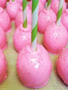 there are many pink cake pops with green and white striped candles on top of them