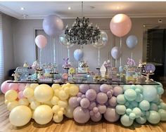 a table topped with lots of balloons next to a wall filled with cake and candy