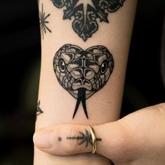 a person with a tattoo on their arm holding a knife in the shape of a heart