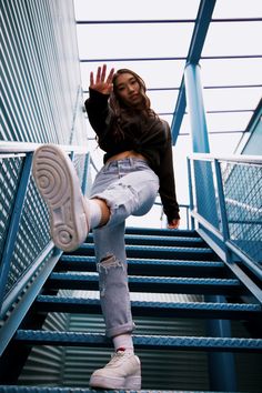 a woman standing on top of a set of stairs with her hands in the air