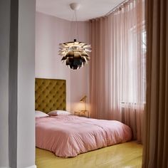 a bedroom with pink bedding and a chandelier