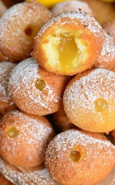 powdered sugar covered donuts piled on top of each other with lemons in the background