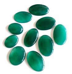 six large green stones sitting on top of a white surface