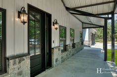 the front porch of a house with two lamps on it's sides and an awning