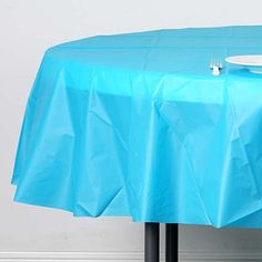 a blue table cloth with a white plate and fork sitting on it next to a wall