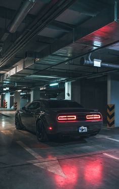 a black sports car parked in a parking garage with red lights on the taillights