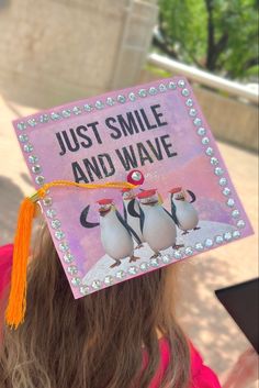 a girl wearing a pink graduation cap with penguins on it's side and the words just smile and wave