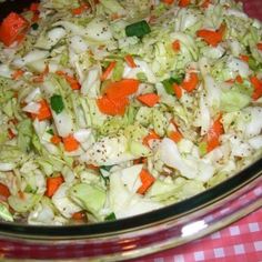 a bowl filled with coleslaw and carrots on top of a checkered table cloth