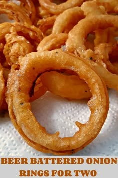 some onion rings sitting on top of a white paper towel with the words beer battered onion rings for two