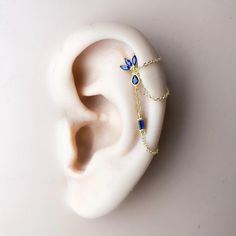 an ear with a chain attached to it and some blue beads hanging from the side