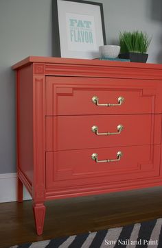 an orange dresser with three drawers in the middle and a potted plant on top