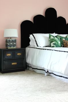 a bedroom with a black headboard and two nightstands in front of the bed