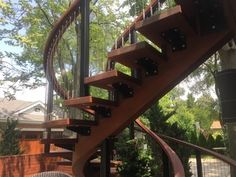 a wooden spiral staircase next to a tree