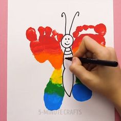 a hand holding a marker and drawing on a piece of paper with the image of a butterfly