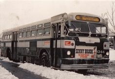 an old black and white bus parked on the side of the road in the snow