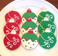 decorated christmas cookies on a white plate with green and red ornaments in the shape of baubles