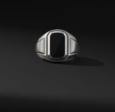 a silver ring with a black stone in the center on a dark background, 3d rendering