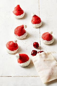 small red and white santa hats sitting on top of a table next to a bag