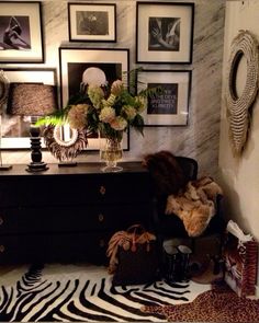 a zebra print rug in front of a dresser with pictures on the wall behind it