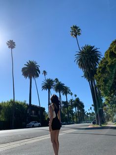 a woman in a bathing suit riding a skateboard down a street next to palm trees