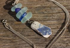 three sea glass necklaces on a wooden table with a chain attached to the clasp