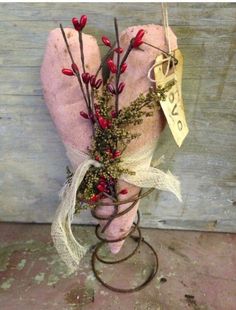 a pink heart shaped object with red berries on it's head and ribbon around the neck