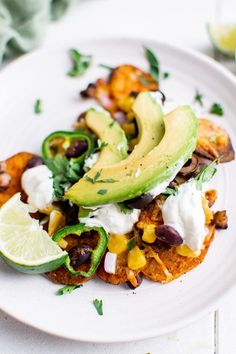 a white plate topped with an enchilada covered in sour cream and avocado