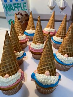 some cupcakes with cones on top of them sitting on a table next to a box of waffle cones