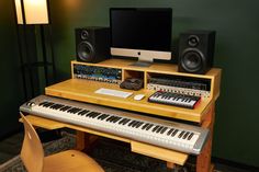 an electronic keyboard sitting on top of a wooden desk next to a computer monitor and speakers