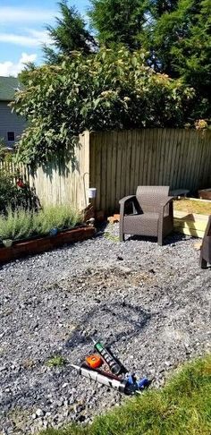 there is a chair and some plants in the back yard with gravel on the ground