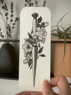 a person holding up a card with a knife and flowers on it