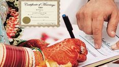 a person signing a marriage certificate on top of a book