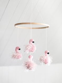 three pink flamingos are hanging from a circular light fixture with white feathers on it